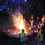 a campfire with children around it toasting marshmallows
